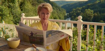 Movie still from “Sex Education” (2019), created by Laurie Nunn – A woman sitting at a table reading a newspaper; Medium shot, Over the shoulder angle