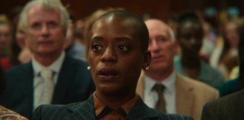 Movie still from “Sex Education” (2019), created by Laurie Nunn – A woman in a suit and tie looking at the camera; Close Up shot, Over the shoulder angle