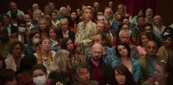Movie still from “Sex Education” (2019), created by Laurie Nunn – A crowd of people sitting and standing in a room; Medium shot, High angle
