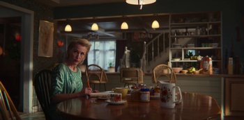 Movie still from “Sex Education” (2019), created by Laurie Nunn – A woman sitting at a dining table writing on a piece of paper; Medium shot, Over the shoulder angle