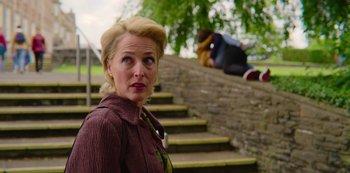Movie still from “Sex Education” (2019), created by Laurie Nunn – A woman standing next to a set of stairs; Medium shot, Over the shoulder angle