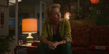 Movie still from “Sex Education” (2019), created by Laurie Nunn – A woman sitting on top of a couch in a living room; Medium shot, Over the shoulder angle