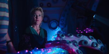 Movie still from “Sex Education” (2019), created by Laurie Nunn – A woman standing in front of a table with lights on top of it; Medium shot, Over the shoulder angle