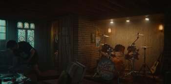 Movie still from “Sex Education” (2019), created by Laurie Nunn – A room with a brick wall and a drum set; Wide shot, High angle
