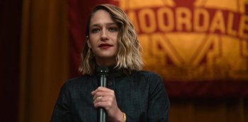 Movie still from “Sex Education” (2019), created by Laurie Nunn – A woman is holding a microphone in her hand; Close Up shot, Over the shoulder angle