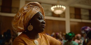 Movie still from “Sex Education” (2019), created by Laurie Nunn – An older woman wearing a head scarf and earrings; Close Up shot, Over the shoulder angle