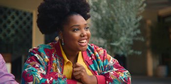 Movie still from “Sex Education” (2019), created by Laurie Nunn – A woman in a colorful jacket smiling for the camera; Close Up shot, Over the shoulder angle