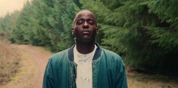 Movie still from “Sex Education” (2019), created by Laurie Nunn – A man with his eyes closed in front of some trees; Close Up shot, High angle