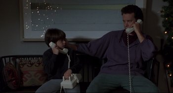 Movie still from “Sleepless in Seattle” (1993), directed by Nora Ephron – A man and a boy sitting next to each other on a phone; Medium shot, Low angle