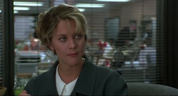 Movie still from “Sleepless in Seattle” (1993), directed by Nora Ephron – A woman sitting in front of a window in an office setting; Close Up shot, Over the shoulder angle