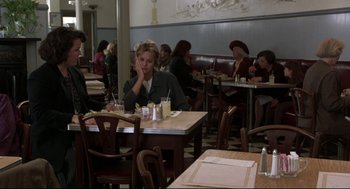 Movie still from “Sleepless in Seattle” (1993), directed by Nora Ephron – A woman sitting at a table in front of a group of people; Medium shot, High angle