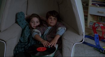 Movie still from “Sleepless in Seattle” (1993), directed by Nora Ephron – Two children are laying on a couch with a record player; Medium shot, High angle