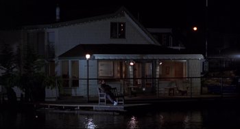 Movie still from “Sleepless in Seattle” (1993), directed by Nora Ephron – A man sitting on a chair in front of a house at night; Wide shot, High angle