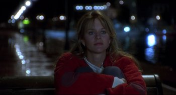 Movie still from “Sleepless in Seattle” (1993), directed by Nora Ephron – A woman sitting on a bench at night with lights in the background; Medium shot, Low angle