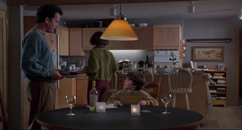 Movie still from “Sleepless in Seattle” (1993), directed by Nora Ephron – A man and a woman standing at a table with a bottle of wine; Medium shot, Over the shoulder angle