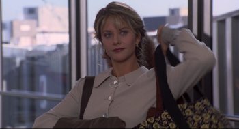 Movie still from “Sleepless in Seattle” (1993), directed by Nora Ephron – A woman holding onto a purse while standing in front of a window; Medium shot, Over the shoulder angle