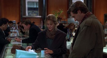 Movie still from “Sleepless in Seattle” (1993), directed by Nora Ephron – A woman is wrapping a present for a man in a suit; Medium shot, Over the shoulder angle