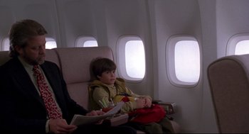 Movie still from “Sleepless in Seattle” (1993), directed by Nora Ephron – A young boy sitting on a seat on an airplane; Medium shot, Over the shoulder angle