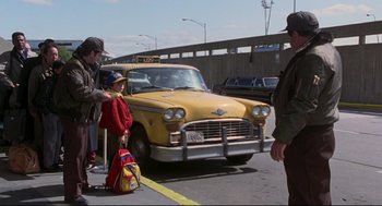 Movie still from “Sleepless in Seattle” (1993), directed by Nora Ephron – A yellow taxi cab driving down a street next to a bridge; Wide shot, Over the shoulder angle