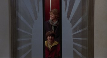 Movie still from “Sleepless in Seattle” (1993), directed by Nora Ephron – A woman standing next to a young boy in an elevator; Medium shot, Low angle