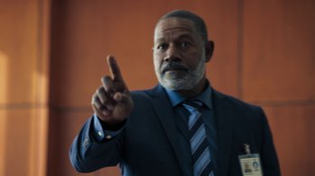 Movie still from “Sniper: Rogue Mission” (2022), directed by Oliver Thompson – A man in a suit and tie pointing to the side; Close Up shot, Low angle