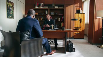 Movie still from “Sniper: Rogue Mission” (2022), directed by Oliver Thompson – Two men sitting at a desk in front of each other; Wide shot, High angle