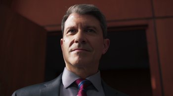 Movie still from “Sniper: Rogue Mission” (2022), directed by Oliver Thompson – A person wearing a suit and tie; Close Up shot, Low angle