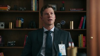 Movie still from “Sniper: Rogue Mission” (2022), directed by Oliver Thompson – A man wearing a suit and tie in a room; Close Up shot, Over the shoulder angle