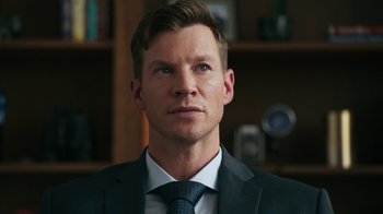 Movie still from “Sniper: Rogue Mission” (2022), directed by Oliver Thompson – A person wearing a suit and tie; Close Up shot, Over the shoulder angle