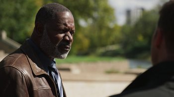 Movie still from “Sniper: Rogue Mission” (2022), directed by Oliver Thompson – An older man wearing a leather jacket and a tie; Close Up shot, Over the shoulder angle