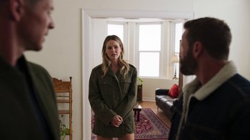 Movie still from “Sniper: Rogue Mission” (2022), directed by Oliver Thompson – A woman standing in front of a man in a living room; Medium shot, Over the shoulder angle