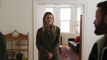 Movie still from “Sniper: Rogue Mission” (2022), directed by Oliver Thompson – A woman standing in a living room in front of a couch; Medium shot, Over the shoulder angle