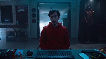Movie still from “Sniper: Rogue Mission” (2022), directed by Oliver Thompson – A man sitting in front of a computer keyboard; Medium shot, High angle