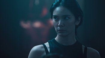 Movie still from “Sniper: Rogue Mission” (2022), directed by Oliver Thompson – A woman in a black shirt is looking into the distance; Close Up shot, Over the shoulder angle