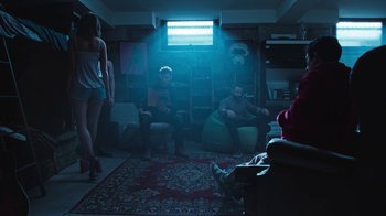 Movie still from “Sniper: Rogue Mission” (2022), directed by Oliver Thompson – A group of people sitting in a living room; Wide shot, Low angle