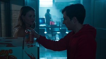 Movie still from “Sniper: Rogue Mission” (2022), directed by Oliver Thompson – A man is holding a can of soda in front of a woman; Medium shot, Over the shoulder angle