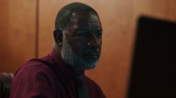 Movie still from “Sniper: Rogue Mission” (2022), directed by Oliver Thompson – An older black man with a gray beard looking at a mirror; Close Up shot, Low angle