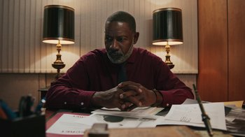 Movie still from “Sniper: Rogue Mission” (2022), directed by Oliver Thompson – A man sitting at a table in front of papers; Medium shot, Over the shoulder angle