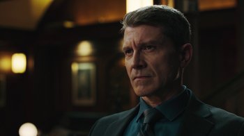 Movie still from “Sniper: Rogue Mission” (2022), directed by Oliver Thompson – A person wearing a suit and tie; Close Up shot, Over the shoulder angle
