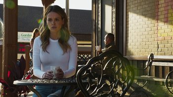 Movie still from “Sniper: Rogue Mission” (2022), directed by Oliver Thompson – A woman sitting at a table holding a coffee mug; Medium shot, Over the shoulder angle