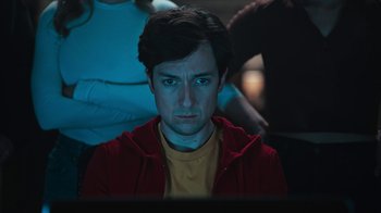 Movie still from “Sniper: Rogue Mission” (2022), directed by Oliver Thompson – A man in a yellow shirt and a red jacket looking at a computer screen; Close Up shot, Low angle