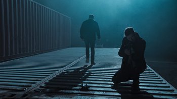 Movie still from “Sniper: Rogue Mission” (2022), directed by Oliver Thompson – A man and a woman walking down a train track; Wide shot, Low angle