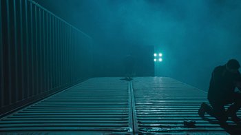 Movie still from “Sniper: Rogue Mission” (2022), directed by Oliver Thompson – A person standing on a platform in the dark; Extreme Wide shot, Low angle