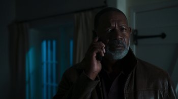 Movie still from “Sniper: Rogue Mission” (2022), directed by Oliver Thompson – An older man talking on a cell phone; Close Up shot, Low angle