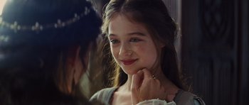 Movie still from “Snow White and the Huntsman” (2012), directed by Rupert Sanders – A young girl smiling while holding her hand to her face; Close Up shot, Over the shoulder angle