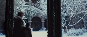 Movie still from “Snow White and the Huntsman” (2012), directed by Rupert Sanders – A person standing in front of a building in the snow; Wide shot, Low angle