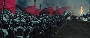 Movie still from “Snow White and the Huntsman” (2012), directed by Rupert Sanders – A large group of people are holding flags and standing in a field; Extreme Wide shot, High angle
