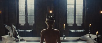 Movie still from “Snow White and the Huntsman” (2012), directed by Rupert Sanders – A woman with a crown is standing in a dark room; Wide shot, Low angle