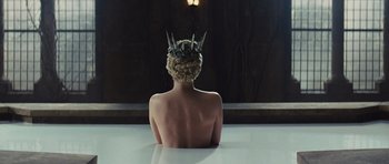 Movie still from “Snow White and the Huntsman” (2012), directed by Rupert Sanders – A woman with a crown sitting on top of a table; Wide shot, Overhead angle