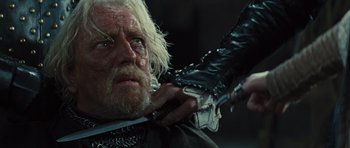 Movie still from “Snow White and the Huntsman” (2012), directed by Rupert Sanders – An old man is holding a knife in his hand; Close Up shot, Over the shoulder angle